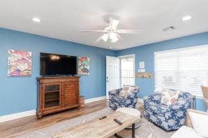 a living room with blue walls and a flat screen tv at The Oasis - Pet Friendly Optional Golf Cart in Port Aransas
