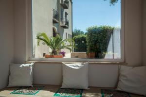 a window with pillows and a view of a plant at Hotel Baia Del Capitano in Cefalù