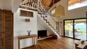 Una sala de estar con una escalera y un televisor. en Villa Amazi, en Andilana