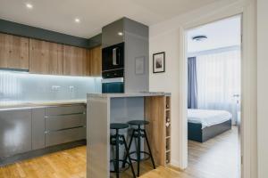 a kitchen with a bar with stools and a bed at Ilidža Luxe Apartment in Sarajevo