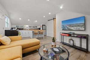 a living room with a couch and a tv on a wall at Ocean-View, Deck, Steps to Beach Dining and More in Solana Beach