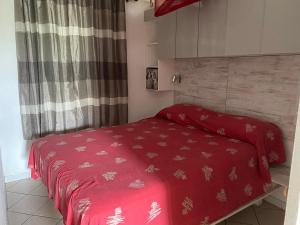 un letto con piumone rosso in una camera da letto di Villas Créoles a Sainte-Anne