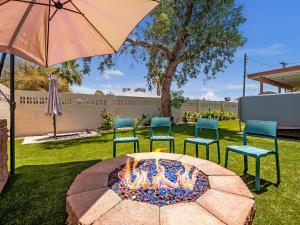 a fire pit with four chairs and an umbrella at 5BR Sleeps 10 Hot Tub Fire Pit Games & Walk to ASU in Tempe