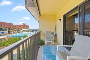 a balcony with a view of a pool and the ocean at Flip Flop Foray at Cocoa Beach in Cocoa Beach