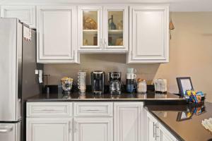a kitchen counter with white cabinets and a refrigerator at Flip Flop Foray at Cocoa Beach in Cocoa Beach