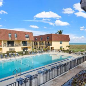 a swimming pool at a resort with tables and chairs at 2BR Sleeps 6 Pool BBQ Steps to Beach Pier Downtown in Cocoa Beach