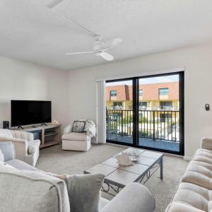 a living room with white furniture and a large window at 2BR Sleeps 6 Pool BBQ Steps to Beach Pier Downtown in Cocoa Beach