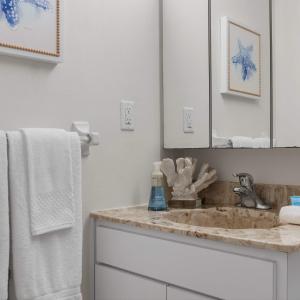 a bathroom with a sink and a mirror and towels at 2BR Sleeps 6 Pool BBQ Steps to Beach Pier Downtown in Cocoa Beach +35 photos