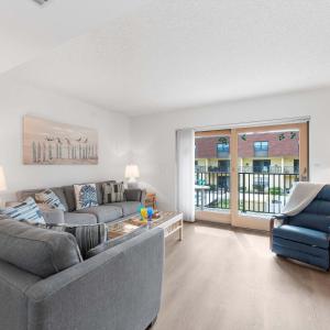 a living room with a couch and a table at Beachfront 2BR Condo with Pool BBQ & Steps To Beach in Cocoa Beach