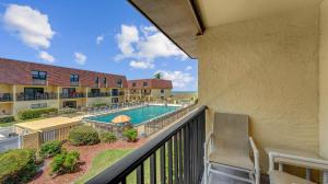 ココアビーチにある2BR Beachfront Condo with Pool BBQ & Steps To Pierのスイミングプールを望むバルコニー