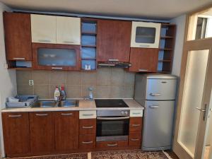 Una cocina con gabinetes de madera, un fregadero y un refrigerador. en Stan Kosevsko Brdo, en Sarajevo