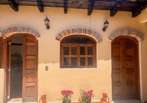 un edificio con dos puertas y dos ventanas y flores en Casa Real de Mexicanos, en San Cristóbal de Las Casas