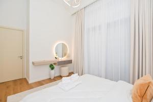 迪拜GV Holiday Homes DXB - Cozy 2BR Apartment in Town Square Dubai的一间带床和镜子的白色卧室 更多19张照片