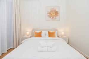 迪拜GV Holiday Homes DXB - Cozy 2BR Apartment in Town Square Dubai的白色卧室配有带橙色枕头的大型白色床