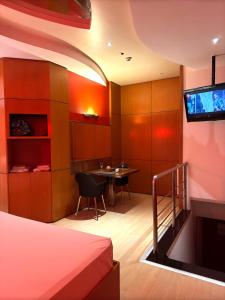 une chambre avec un lit et une table avec une télévision dans l'établissement Lumini Motel, à São Paulo