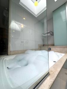 La salle de bains est pourvue d'une baignoire et d'une paroi en verre. dans l'établissement Lumini Motel, à São Paulo
