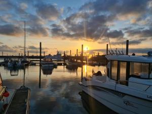 eine Gruppe von Booten, die bei Sonnenuntergang in einem Yachthafen angedockt sind in der Unterkunft Lüttjer Kaiser Comfortable holiday residence in Norderney