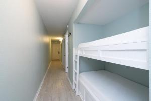 a bedroom with white bunk beds and a hallway at 1BR Sleeps 5 at The Summit with Ocean Front Views in Panama City Beach