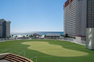 Un campo de golf al lado de un edificio con el océano. en Whitesands Retreat - Incredible Resort Home, en Panama City Beach