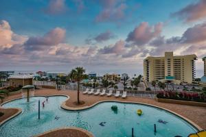 una piscina en un complejo con sillas y apartamentos en condominio en Whitesands Retreat - Incredible Resort Home, en Panama City Beach