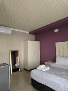 a bedroom with a bed and a purple wall at Lido System Makonde Village in Thohoyandou