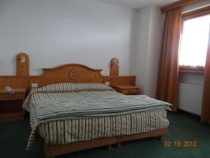 a bedroom with a bed with a wooden headboard and a window at Hotel Mondeval in Selva di Cadore
