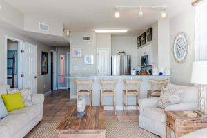 a living room with a couch and a kitchen at Sunset Shores - Oceanfront Condo Bliss in Panama City Beach