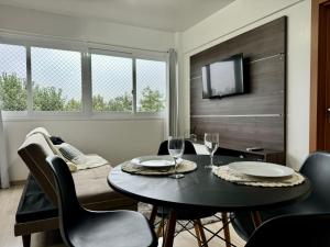 a dining room with a table and chairs and a tv at Paz, vinho e conforto in Bento Gonçalves