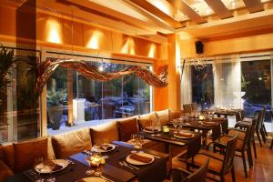 een restaurant met tafels en stoelen en een groot raam bij Theoxenia Residence in Athene