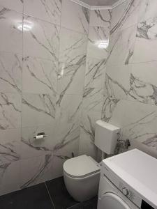 a white bathroom with a toilet and a sink at Apartman LENA in Trebinje