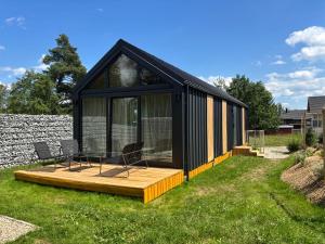 a black house with a wooden deck in a yard at Tiny House at Deer Trail Tatranska Lomnica in Tatranská Lomnica
