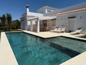a villa with a swimming pool in front of a house at Mirador las Cumbres Conil - Piscina Jardín XL in Conil de la Frontera