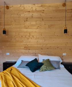 a bed with two pillows on it with a wooden wall at Villa Rosina in Saint Vincent