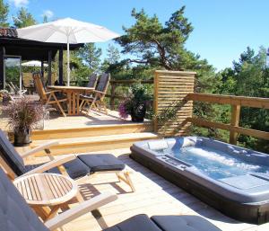 a deck with a hot tub and a table and chairs at 5-star homestay for 2 with breakfast, hot-tub, aircon and bikes in Ingarö