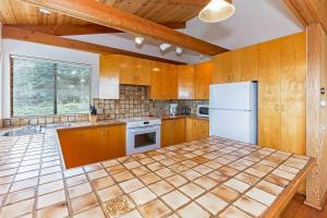 a kitchen with wooden cabinets and a white refrigerator at Seaclusion - Close to Trails - Hot Tub in Sea Ranch