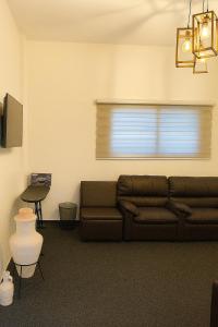 een woonkamer met een bruine bank en een raam bij Beit Ahlam Quiet Duplex Villa with Terrace and Scenic View near Umm Qais Ruins in Um Qeis +28 foto's