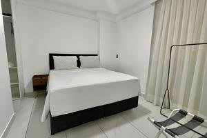 a white bedroom with a bed and a chair at Flat pé na areia c/vista 406B Branco Haus -MyFlats in Tambaú +33 photos
