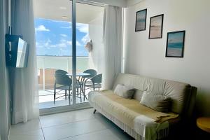 a living room with a couch and a balcony with a table at Flat pé na areia c/vista 406B Branco Haus -MyFlats in Tambaú