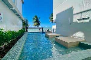 a swimming pool in the middle of a building with the ocean at Flat pé na areia c/vista 406B Branco Haus -MyFlats in Tambaú