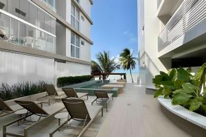 an outdoor patio with chairs and a swimming pool at Flat pé na areia c/vista 406B Branco Haus -MyFlats in Tambaú
