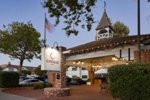 a sign in front of a building with a clock tower at Corque Hotel, Solvang, A Tribute Portfolio Hotel in Solvang