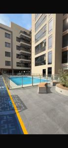 a large building with a swimming pool in front of it at كمباوند ماربيلا الكورنيش شقة in Ar Rākah