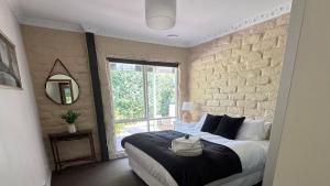 a bedroom with a large bed and a window at Elegant Country Living - The Homestead by Scotch Hill Truffle Farm in Neerim South