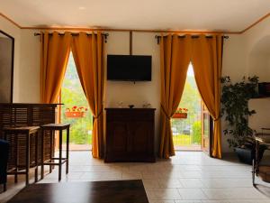 un salon avec des rideaux orange et une télévision à écran plat dans l'établissement Sunrise Inn & Campo da Tennis, à Mezzenile 5 autres photos