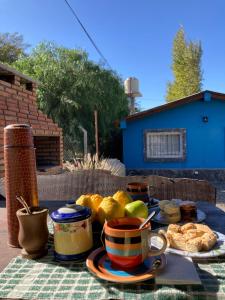 a table with a plate of food and cups and fruit at Cabañas Pukara in Cafayate