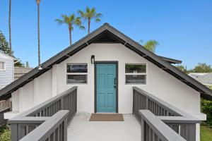 a white house with a blue door and palm trees at Ocean-View, Deck, Steps to Beach Dining and More in Solana Beach