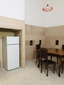 Una cocina con una mesa y un refrigerador blanco. en Dimora Aragona, en Tuglie