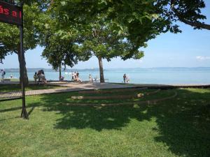 a park with people sitting on the grass near the water at Apartment in Zamardi - Balaton 33875 in Zamárdi
