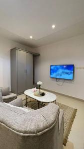 a living room with a table and a tv on the wall at شقة اسـتـديو أنـيـق بـدخول ذاتـي in Al Kharj