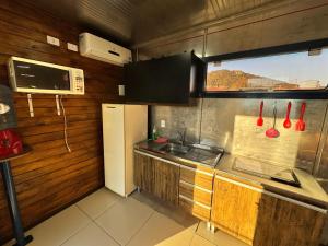 a kitchen with a white refrigerator and a microwave at Pousada Container Guarda do Embaú in Palhoça